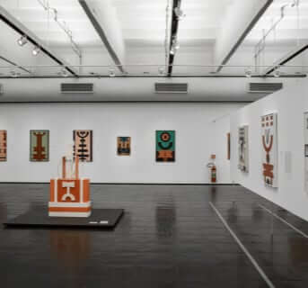 Gallery room showcasing a collection of paintings with a sculpture prominently placed in the center